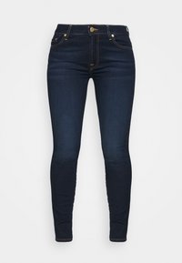 Vaqueros ajustados de color azul oscuro, hechos de denim, con cinco bolsillos, una cinturilla estándar y detalles de costura dorada.