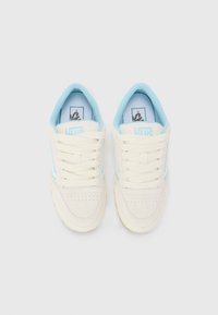 Vans sneakers with a cream canvas upper, light blue accents, rounded toe, and perforated details. White laces and rubber sole.