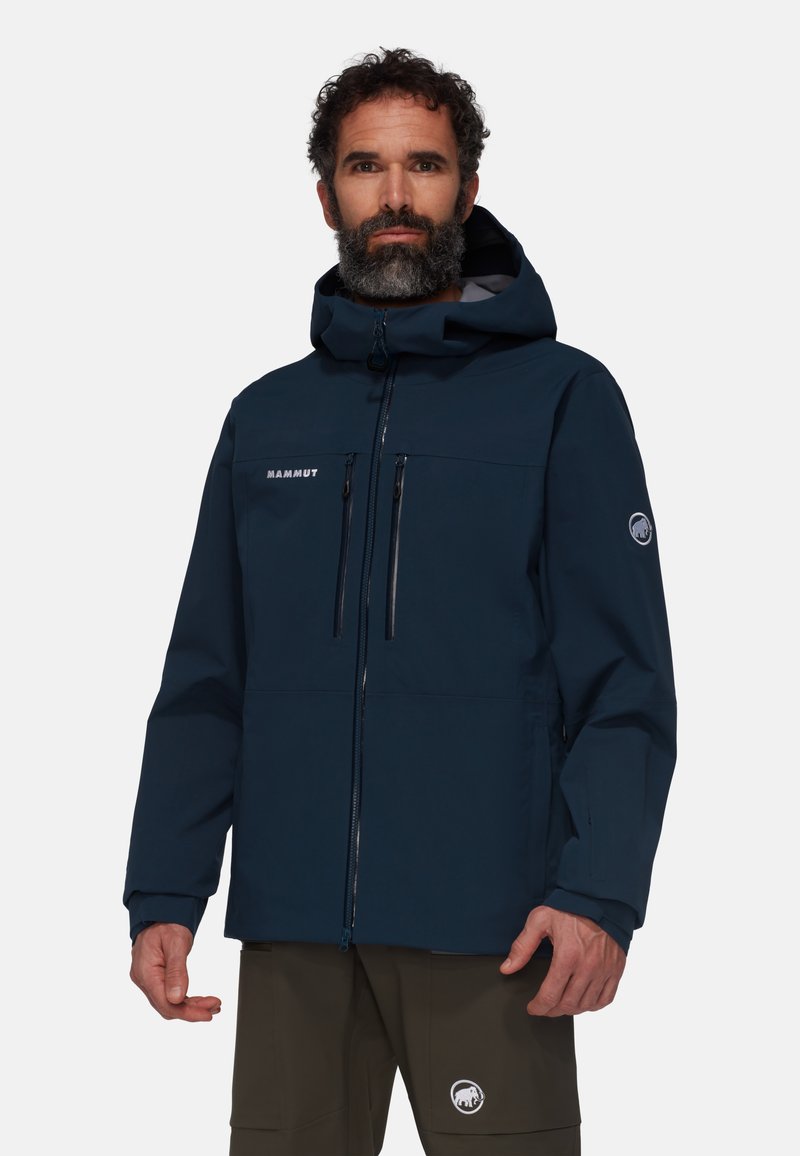 Veste imperméable bleu marine avec capuche, fermeture éclair sur le devant, deux poches poitrine et détail de logo sur la manche. Tissu durable avec une texture lisse.