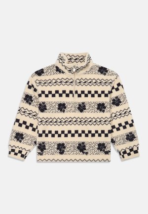 Pull en polaire avec un col zippé quart en crème, présentant des motifs géométriques et floraux noirs, des accents côtelés et une texture douce.