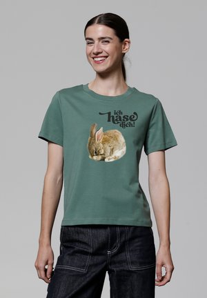 Groene katoenen t-shirt met een afgedrukte slapende konijn en de tekst "ich hasse dich!" in vetgedrukte zwarte letters, met een ronde hals en korte mouwen.