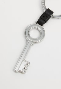 Silver key-shaped keychain with a round ring, featuring a black leather accent at the joint, smooth surface and symmetrical design.