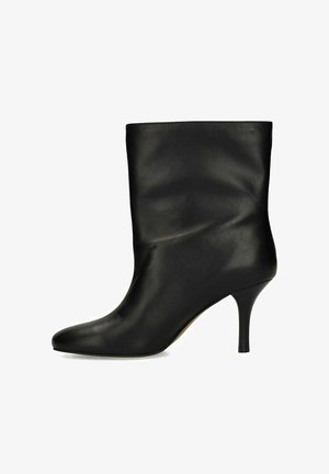 Botte pour femme en cuir noir mi-mollet avec bout pointu et talon haut élancé sur fond blanc.