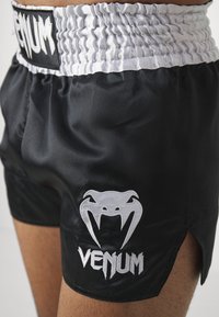 Črne satenske kratke hlače z belim elastičnim pasom, z belim logotipom in napisom Venom na levi nogi, ter stranskimi razporki za boljšo gibljivost.