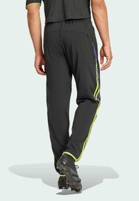 Czarne spodnie dresowe z zielonymi i fioletowymi paskami po bokach, elastycznym pasem, kieszenią na zamek i zwężanymi nogawkami, zaprojektowane z myślą o maksymalnym komforcie.