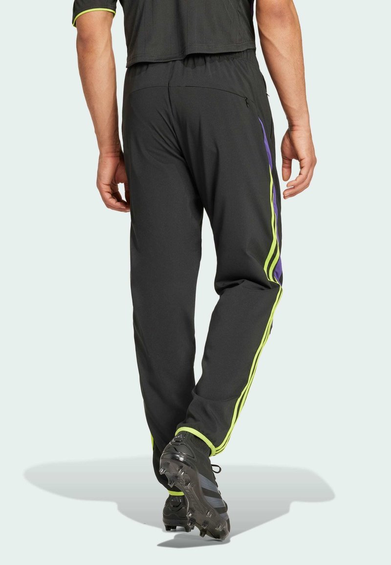 Pantalones deportivos negros con rayas laterales verdes y moradas, cintura elástica, bolsillo con cremallera y tobillos ajustados, diseñados para un confort óptimo.