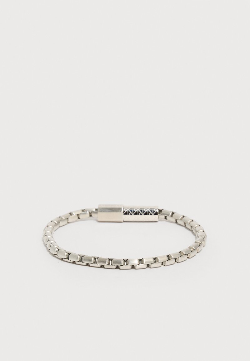 Βραχιόλι από μέταλλο σε ασημί απόχρωση με ορθογώνιους κρίκους και μαγνητικό κούμπωμα που διαθέτει γεωμετρικό μαύρο και ασημί σχέδιο.