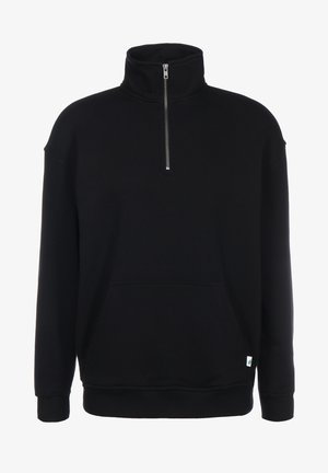 Schwarzer Pullover mit halber Reißverschlussfront, hohem Kragen, langen Ärmeln, Kängurutasche und kleinem grünen Blattanhänger am Saum.