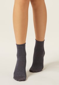 Grå ankelstrumpor av ett skimrande material, med ribbad mudd och en mjuk, len yta.