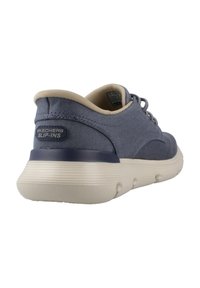 Marineblauwe Skechers instap schoenen met een textuurstof bovenkant, beige accenten en een dikke witte rubberen zool met ronde profielpatronen.