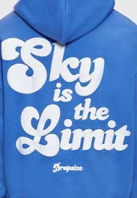 Sweat à capuche bleu avec grand texte blanc disant « Sky is the Limit » et texte plus petit « Dropsize » au dos.