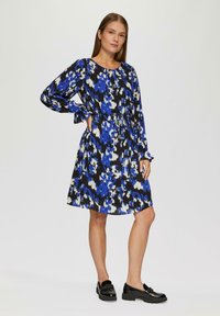 Langarm jurk met een abstracte print in blauw, zwart en wit. Het ontwerp heeft een ronde halslijn en een geplooide taille.
