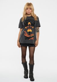 Black graphic t-shirt featuring a David Bowie design with orange and yellow accents. Paired with a black denim skirt and knee-high boots.