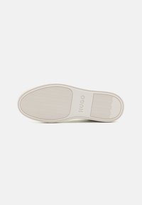 Semelle de chaussure en caoutchouc blanc avec un motif texturé. Présente la marque "HUGO" et des bords arrondis. Design lisse et épuré adapté à une utilisation décontractée.