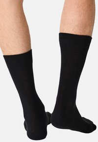 Sorte midt-på-låret sokker lavet af et blødt, elastisk materiale. Glat finish med ribbet kant og sømløs tådesign.