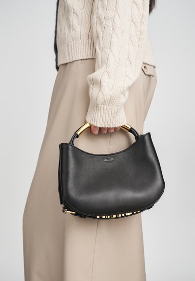 Črna usnjena torbica s ukrivljenim dizajnom, z zlatim okovjem in teksturiranim zgornjim ročajem. Torbica ima dekorativni zlat akcent na dnu.