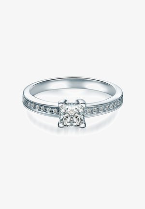 Strieborný zásnubný prsteň s diamantom brúseným do tvaru princeznej, ktorý je zasadený v priesečníku, a s malými okrúhlymi diamantmi zasadenými po obvode prsteňa pre zvýšenú iskru.
