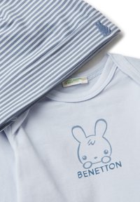 Body per neonati blu chiaro con un coniglio dei cartoni animati e il testo "BENETTON", abbinato a un tessuto a righe blu e bianche con un piccolo ricamo di coniglio.