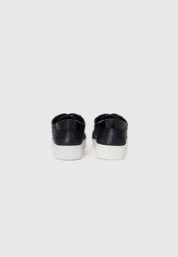 Zwarte leren sneakers met een gladde textuur, witte rubberen zolen en een minimalistisch ontwerp. Inclusief dubbele hieltabs voor gemakkelijke toegang.