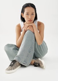 Sneakers with a textured snake print pattern in shades of beige and brown, featuring a white rubber sole and black laces.