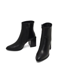 Bottines en cuir noir à bouts pointus, fermeture éclair et talons carrés. Texture lisse et design épuré avec des accents minimaux.