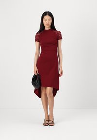 Rochie ajustată bordó cu mâneci scurte din dantelă și tiv înalte și joase. Însoțită de o poșetă neagră tip clutch și sandale negre cu bretele.
