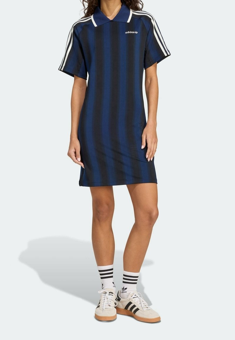 Robe polo rayée bleu marine à coupe ample, manches courtes et accents blancs. Assortie à des chaussettes blanches ornées de rayures noires et des baskets.