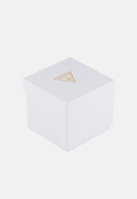 Valkoinen neliölaatikko, jossa on teksturoitu pinta ja kultainen kolmion muotoinen logo päällä. Yksinkertainen, siisti muotoilu, joka sopii pakkaukseen.