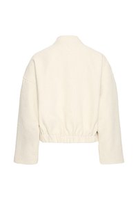 Orezaná krémová bunda s textúrovanou látkou, elastickým pásom a širokými rukávmi. Žiadne viditeľné zapínanie alebo vzory.