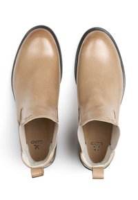 Beige leather slip-on shoes with a smooth finish, rounded toe, contrasting black sole, and a pull tab at the back for easy wear.
