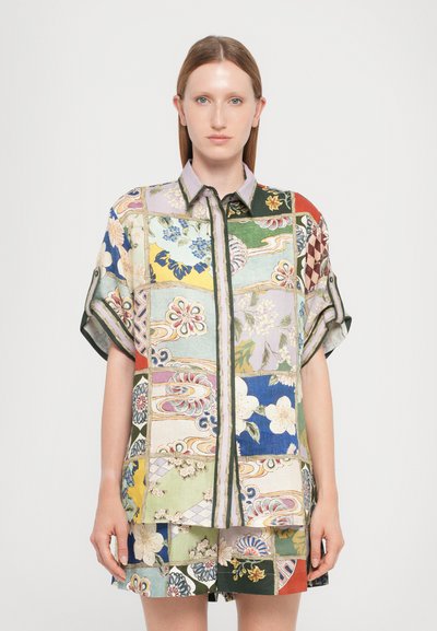 Korte mouw geknoopte shirt met een patchworkontwerp van bloemen- en geometrische patronen in verschillende kleuren, voornamelijk groen, blauw en geel.