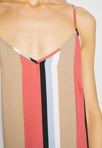 Haut sans manches multicolore avec un décolleté en V. Présente des rayures verticales rouges, noires, bleues et beige avec une texture lisse.