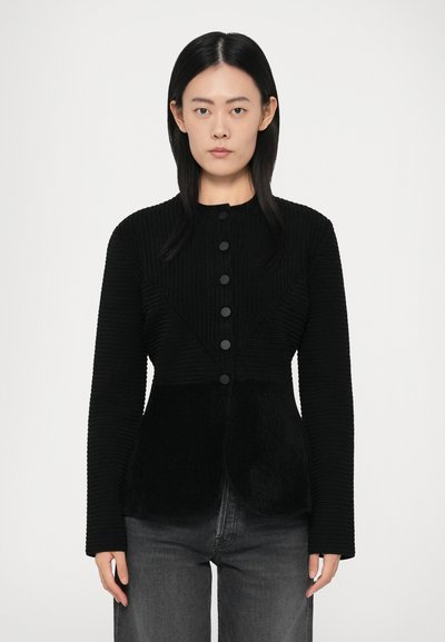 Black ribbed jacket with long sleeves, featuring a round neckline and six black buttons, structured with a fitted design and textured panels.