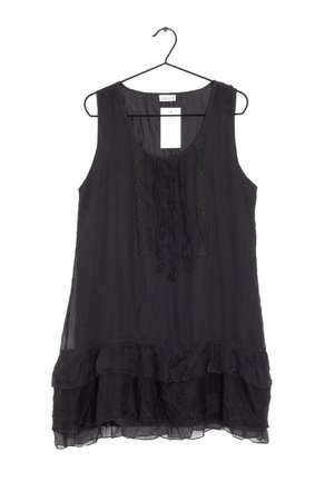 Schwarzes ärmelloses Tunika mit Rüschen am Saum, verziert mit Spitzendetails und einer fließenden Chiffon-Textur. Präsentiert auf einem schwarzen Kleiderbügel.