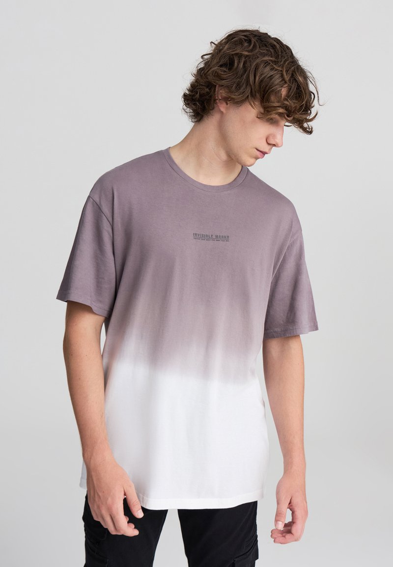 T-shirt in cotone leggero con design a gradiente che va dal viola tenue al bianco, con collo rotondo e maniche corte. Dettagli testuali sul petto.