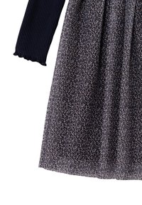 Czarny prążkowany longsleeve w połączeniu z marszczoną spódnicą z drobnym czarno-beżowym wzorem w panterkę.
