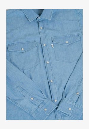 Hellblaues Jeanshemd mit langen Ärmeln, Druckknöpfen, zwei Brusttaschen und Western-Style Passe. Der Stoff hat eine glatte Textur.