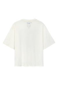 Kremowa bawełniana koszulka z krótkimi rękawami, okrągłym dekoltem i małym niebieskim nadrukiem na plecach w pobliżu dekoltu.