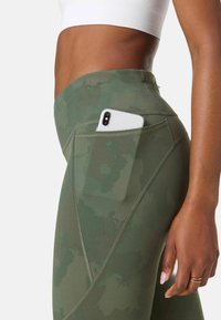 Groene leggings met camouflageprint en een zijvak voor een smartphone. Voorzien van een tailleband en contrasterende stikseldetails. Lichtgewicht, rekbare stof.