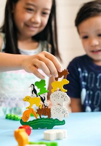 Wooden animal stacking game features colorful pieces with distinct animal shapes, including a penguin, sheep, and alligator, on a blue surface.