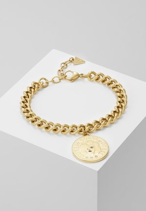 Gold-tone chain bracelet with a round medallion featuring a stylized face and crystal accents, secured by a lobster clasp.