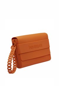 Borsa a tracolla in silicone arancione con motivo testurizzato a nido d'ape. Presenta una robusta tracolla a catena modellata e una chiusura frontale con il nome del marchio.