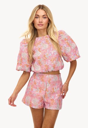 Haut court smocké à fleurs roses avec des manches ballons, associé à un short taille haute assorti. Présente un tissu texturé et des motifs floraux colorés.