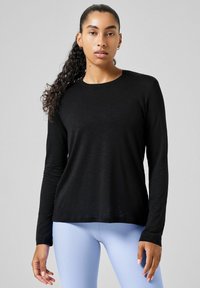 Black long-sleeve shirt with a round neck, made of soft fabric, featuring a straight cut and a lightweight texture. Paired with light blue leggings.