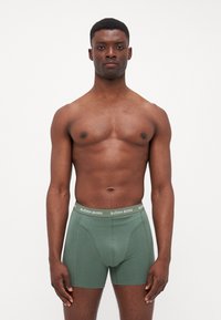 Zöld pamut boxer nadrág, szűk szabással, fehér logós derékkal. Sima textúrájú és testreszabott kialakítással a kényelem érdekében.