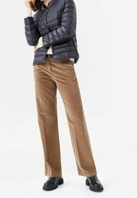 Uppblåst, marinblå jacka med hög krage, tillsammans med tanfärgade manchesterbyxor med vida ben och svarta klackiga stövlar. Texturerad, avslappnad outfit.