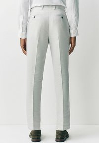 Jasnoszare spersonalizowane spodnie z dwiema tylnymi kieszeniami, w slim fit, o gładkiej fakturze lnu. Zawierają subtelne szwy boczne oraz detale z guzikami.