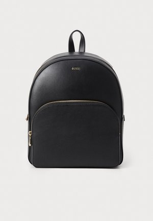 Sac à dos en cuir noir de forme arrondie, doté d'une poche avant avec une fermeture éclair en or et d'une poignée supérieure pour un transport facile.