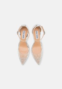 Zapatos de tacón alto plateados con puntera afilada, parte superior transparente y adornados con pequeños strass transparentes. Incluye una correa ajustable para el tobillo.
