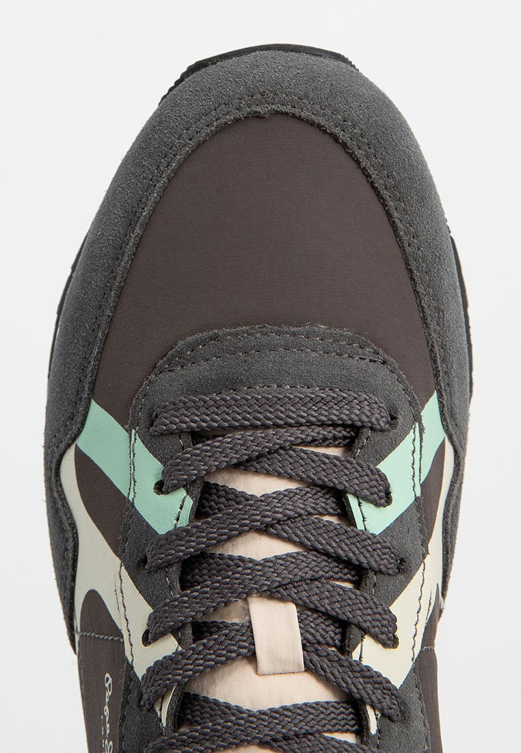 Zapatilla con un upper de ante marrón y tela, que presenta un diseño de franjas en azul verdoso y crema, cordones gris oscuro y una puntera reforzada.